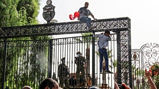 Tunisian soldiers guard the main entrance of the parliament as demonstrators gather outside the the gate in Tunis, Tunisia, Monday, July 26, 2021.