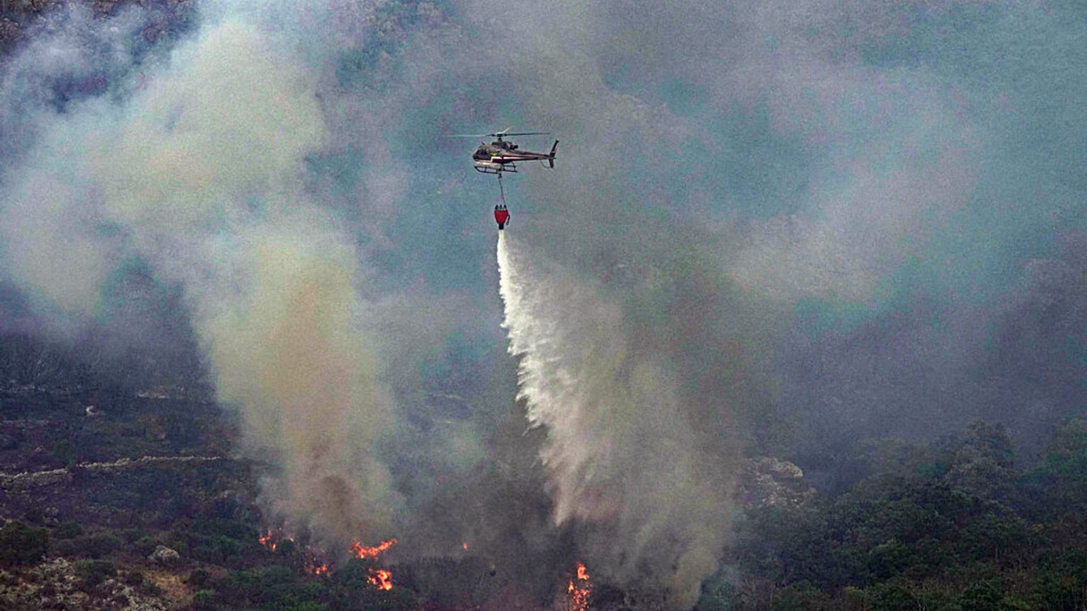 İtalya'nın Sardinya Adası'nda çıkan orman yangınına müdahale eden bir helikopter.