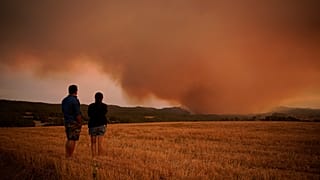 Residents look on as athe forest fire rages near Tarragona.