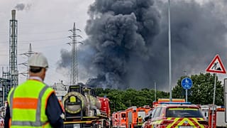 Emergency vehicles stand not far from an access road to the Chempark over which a dark cloud of smoke is rising in Leverkusen, Germany, July 27, 2021.