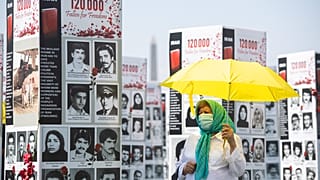 FILE: A woman walks past some of the thousands photos of people killed in Iran during the 1988 massacre of political prisoners, Washington DC, Sept. 2020. 