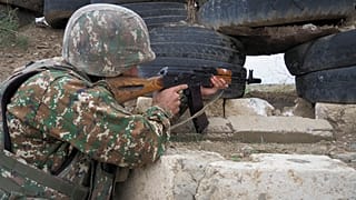 Un soldado armenio sostiene una ametralladora Kalashnikov mientras mira hacia las posiciones de Azerbaiyán
