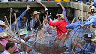 Participants of the Fischertag jump with their 'Baeren' hand nets into the stream in Memmingen.