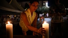 Eine Frau stellt in Pristina in Gedenken an die Opfer eine Kerze auf