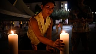 Eine Frau stellt in Pristina in Gedenken an die Opfer eine Kerze auf
