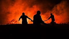 Firefighters and local villagers try to bring a fire under control in the village of Kirli.