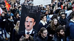 A person holds a placard depicting French President Emmanuel Macron as Adolf Hitler during a 2018 protest against a proposed university reform. 
