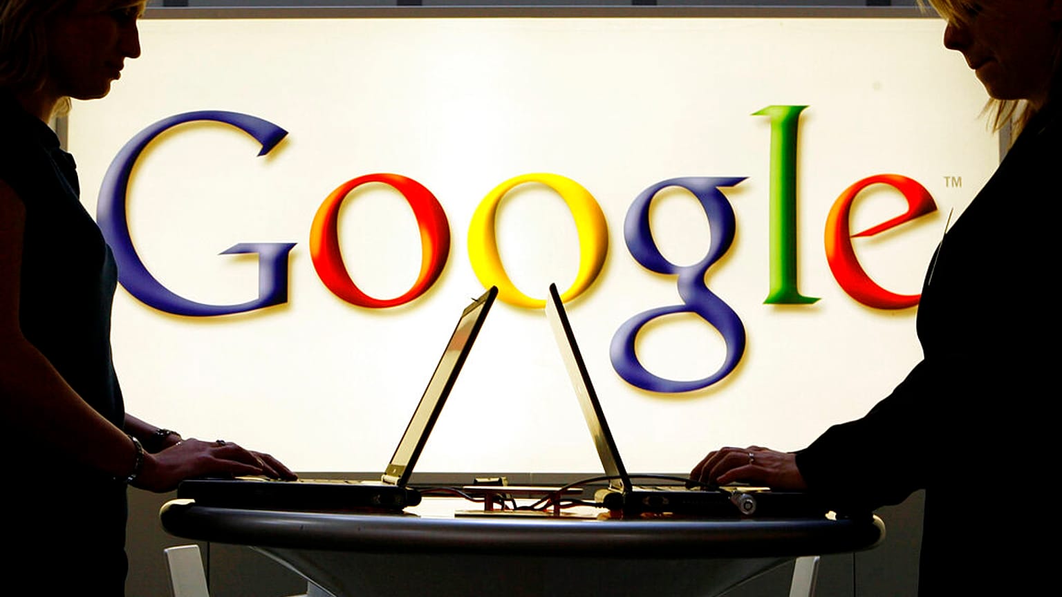 Aussteller arbeiten an Laptops vor einer Leuchtreklame mit dem Google-Logo auf der Industriemesse Hannover Messe in Hannover, 17.04.2007 