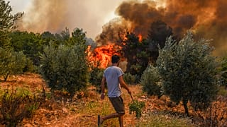 A man walks toward wildfires in Kacarlar village near the Mediterranean coastal town of Manavgat, Antalya, Turkey, Saturday, July 31, 2021.