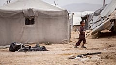 A boy holds a book as he walk at al-Hol camp, which houses families of members of the Islamic State group, in Hasakeh province, Syria, Saturday, May 1, 2021.