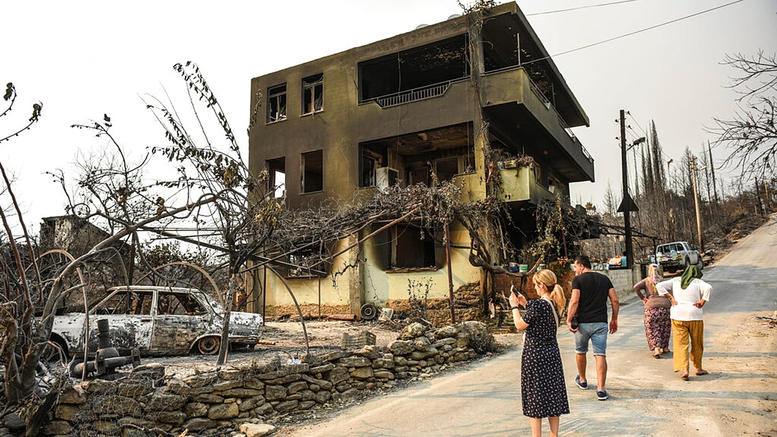 Varias personas caminan por las calles calcinadas de una aldea en Antalya, Turquía.