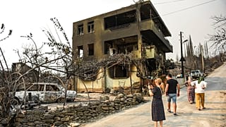 Varias personas caminan por las calles calcinadas de una aldea en Antalya, Turquía.