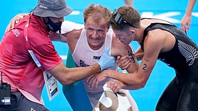 Kristian Blummenfelt being helped by other athletes after winning the 2020 Olympic triathlon.