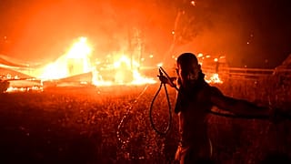 Un hombre lucha contra le fuego en Adames, al norte Atenas, Grecia