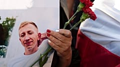 A young woman holds a picture of Belarusian activist Vitali Shishov outside the Belarusian embassy in Kyiv,  August 3, 2021