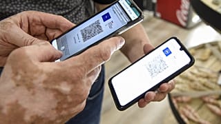 A person uses a pass verification application on a smartphone to check a health pass displayed on a smartphone in Amneville, eastern France, on July 22, 2021.