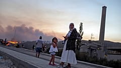 People stand in front of Kemerkoy Thermal Power Plant, right, as a wildfire approaches in the background, in Milas, Mugla, Turkey, Aug. 3, 2021. 