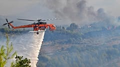 Ein Hubschrauber bekämpft ein Feuer nahe der antiken Olympiastätten