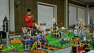 A person stands in front of a Lego metropolis including buildings, shopping complexes, cafes and parks.