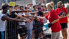Litvánok árucikkeket adnak a menekülőknek a kordonon keresztül a verebiejai tábornál (illusztráció)