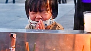 Una bambina prega di fronte al cenotafio di Hiroshima