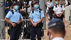 Police officers outside a court July 30, 2021, in Hong Kong, as pro-democracy demonstrator Tong Ying-kit exits after his sentencing for the violation of a security law.