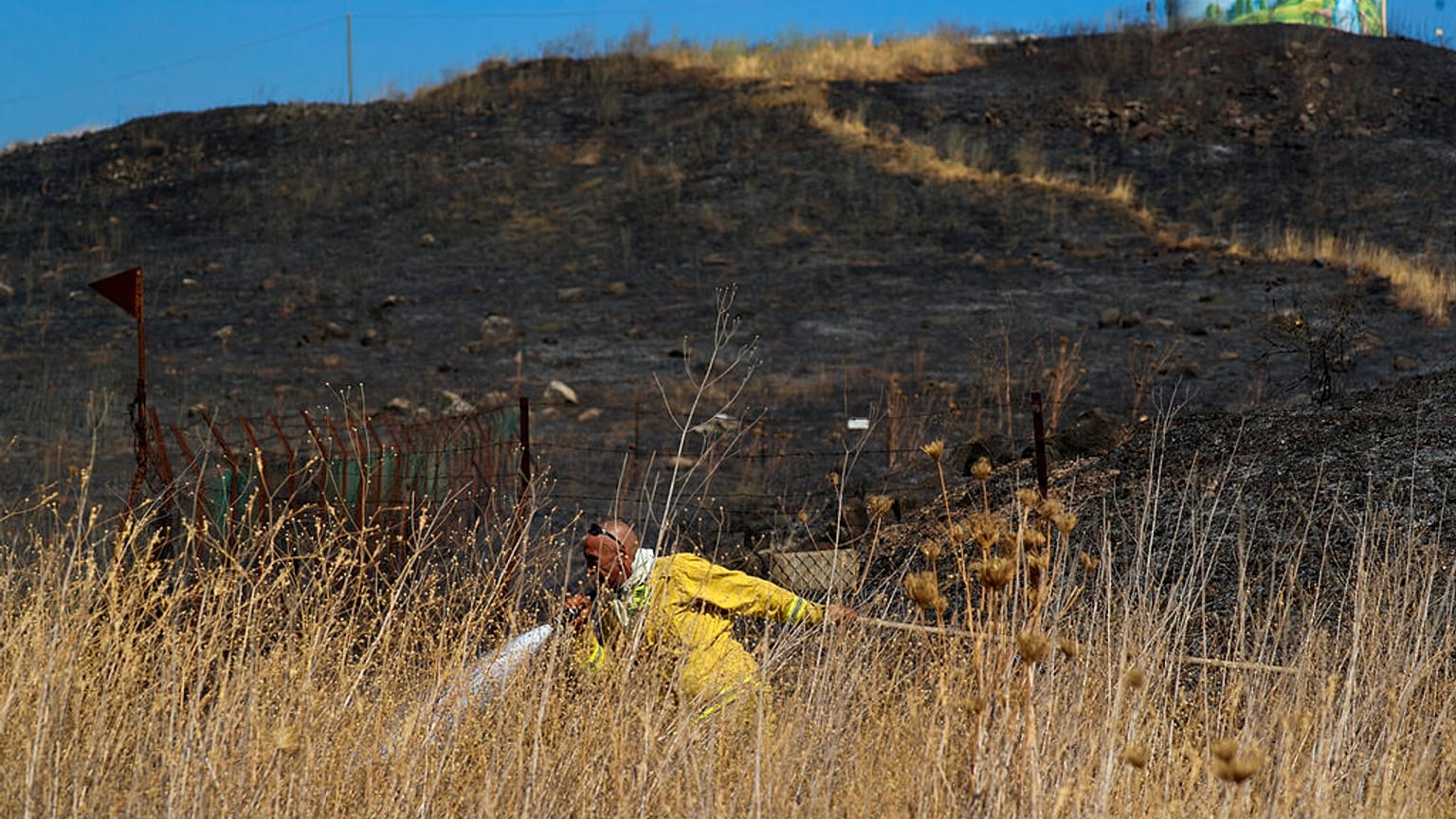 An Israeli firefighter attempts to extinguish a fire caused by rocket fired from Lebanon into Israeli territory near the northern Israeli town of Kiryat Shmona.