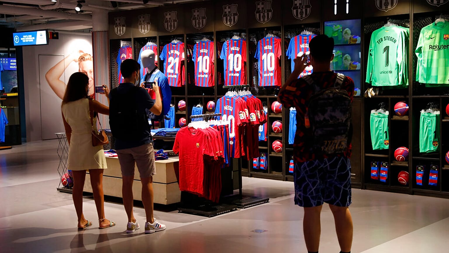 People take photos of Lionel Messi shirts on sale at the club's store before FC Barcelona club President Joan Laporta gives a news conference in Barcelona