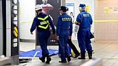 Tokyo Fire Department personnel and a police investigator, right, move toward a platform at Soshigaya Okura Station after stabbing on a commuter train