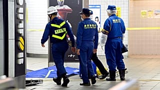 Tokyo Fire Department personnel and a police investigator, right, move toward a platform at Soshigaya Okura Station after stabbing on a commuter train