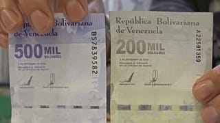 A man shows a one million bolivar note next to a twenty dollar note at a butcher's shop in western Caracas