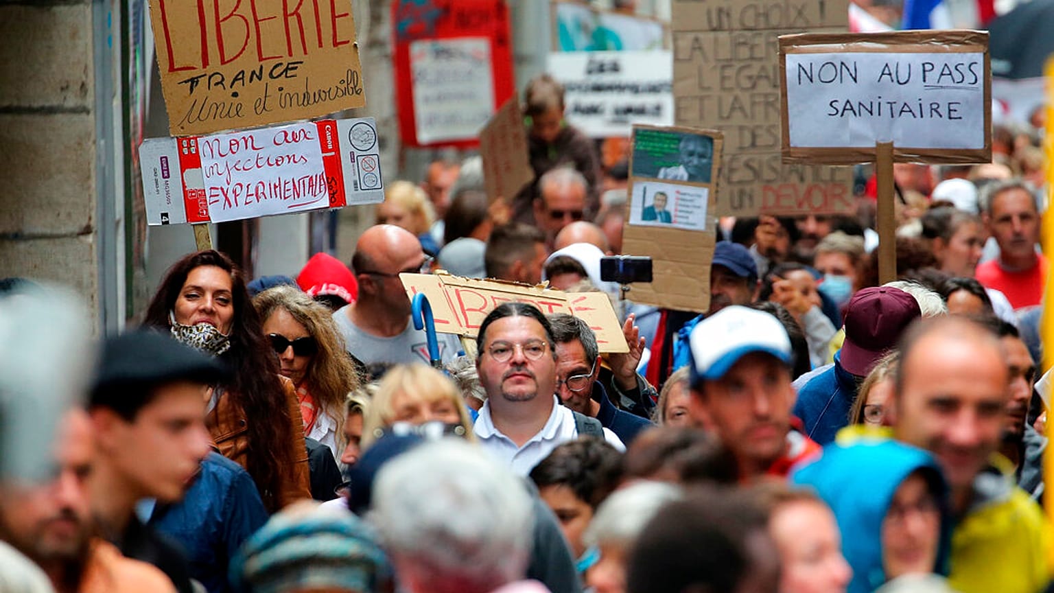 People hold signs reading "liberty" and "no to the sanitary pass" during a protest in Bayonne, southwestern France