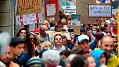 People hold signs reading "liberty" and "no to the sanitary pass" during a protest in Bayonne, southwestern France