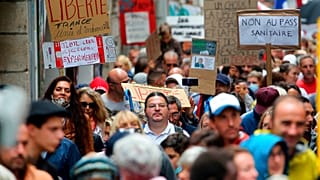People hold signs reading "liberty" and "no to the sanitary pass" during a protest in Bayonne, southwestern France