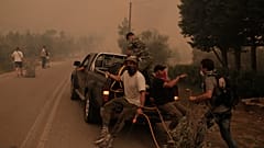 Πολίτες επιβιβάζονται σε υδροφόρο όχημα κατά τη διάρκεια της επιχείρησης κατάσβεσης της πυρκαγιάς στην περιοχή Πευκί στην Βόρεια Εύβοια