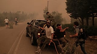Πολίτες επιβιβάζονται σε υδροφόρο όχημα κατά τη διάρκεια της επιχείρησης κατάσβεσης της πυρκαγιάς στην περιοχή Πευκί στην Βόρεια Εύβοια