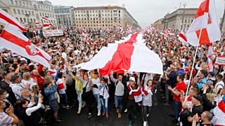 In this Sunday, Aug. 23, 2020 file photo, demonstrators carry a huge historical flag of Belarus as thousands gather for a protest at the Independence square in Minsk, Belarus.