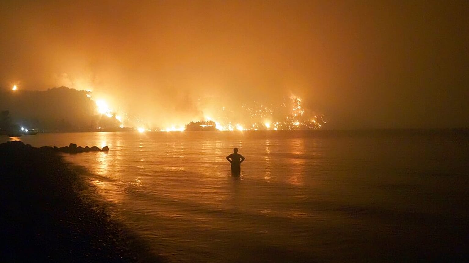 En esta foto de archivo fechada el viernes 6 de agosto de 2021, un hombre observa cómo los incendios forestales se acercan a la playa de Kochyli, en Grecia