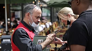 A waiter checks diners' health passes at a restaurant in Paris, 9 August 2021. 