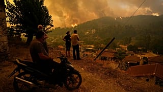 Az Évia szigetén fekvő Gouves lakó nézik a településhez közelítő lángokat egy dombról