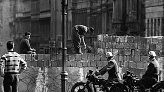 This picture taken in August 1961 shows police officers watch workers lay bricks on the other side of the so called Berlin Wall in the street Bernauer Strasse in Berlin.