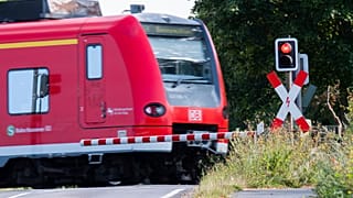 A Deutsche Bahn (DB) commuter train passes a level crossing with a red light in Roessing, Germany, Aug. 11, 2021.