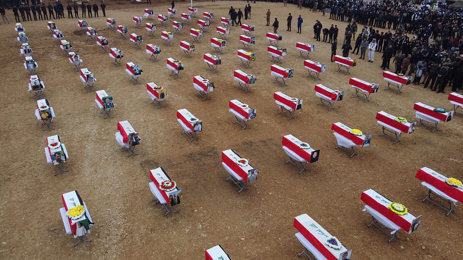 An aerial picture shows mourners gathering around coffins wrapped with the Iraqi flag during a mass funeral for Yazidi victims of the Islamic State (IS) group