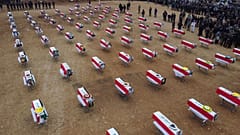 An aerial picture shows mourners gathering around coffins wrapped with the Iraqi flag during a mass funeral for Yazidi victims of the Islamic State (IS) group