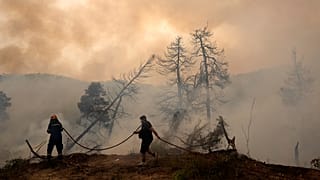 A firefighter tries to extinguish the flames at a village on Evia.