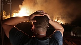 A man looks at a forest fire near the village of Larbaa Nath Irathen, neat Tizi Ouzou, in the mountainous Kabyle region, Algeria, Wednesday, Aug.11, 2021.