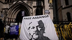 Supporters of WikiLeaks founder Julian Assange hold up a banner as they protest, during the first hearing in the Julian Assange extradition appeal, at the High Court in London
