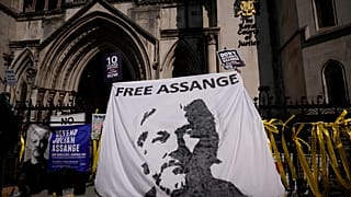 Supporters of WikiLeaks founder Julian Assange hold up a banner as they protest, during the first hearing in the Julian Assange extradition appeal, at the High Court in London