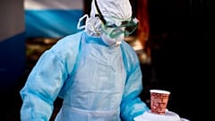 Oct. 8, 2014 photo, a medical worker carries a meal to a man being quarantined after coming into contact  with a carrier of the Marburg Virus