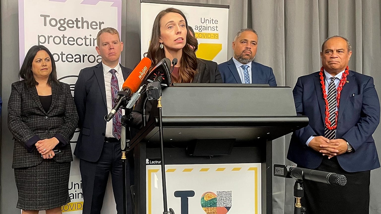 Flanked by lawmakers, New Zealand Prime Minister Jacinda Ardern delivers a speech on Aug. 12, 2021, in Wellington, New Zealand.